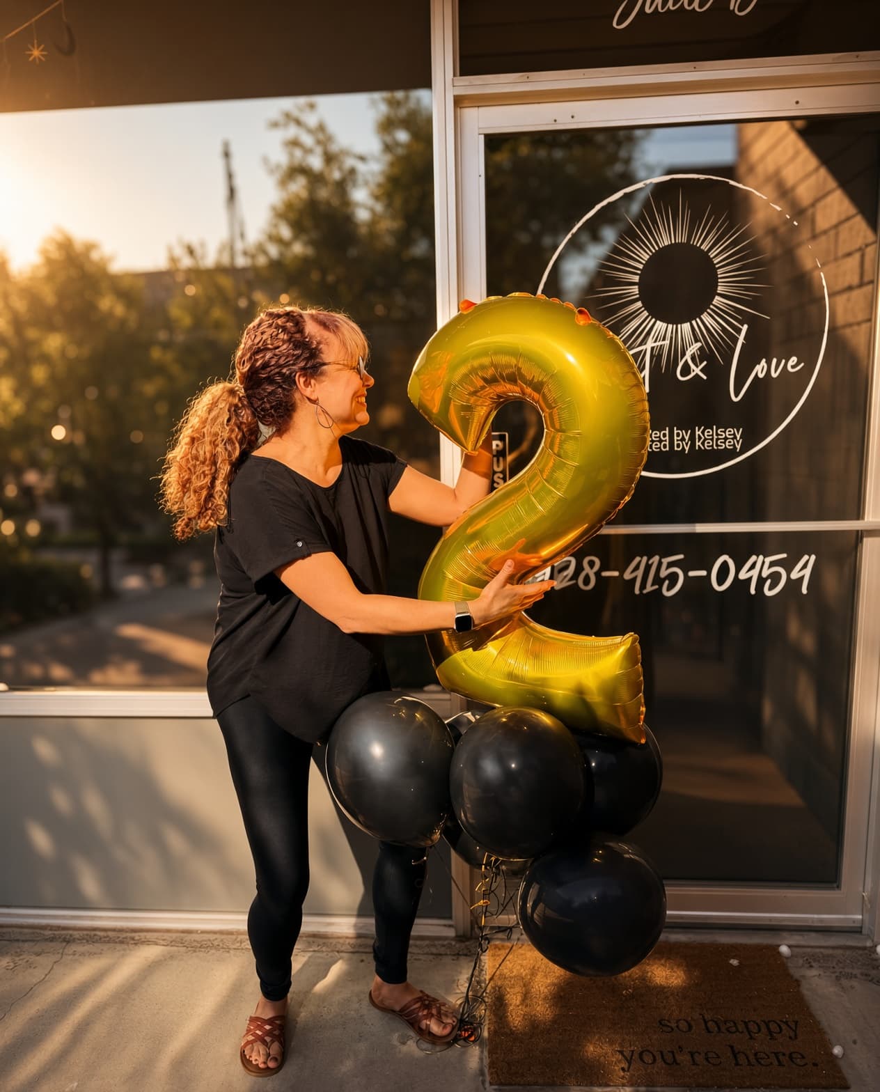 Kelsey at the studio door with a gold number two balloon